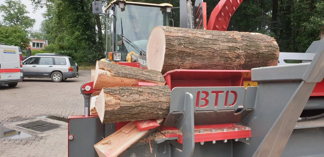 BTD houtklover met Volvo shovel in bedrijf – vers gekloofd haardhout zichtbaar op werkplatform.