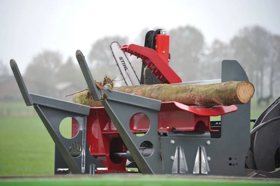 BTD houtkloofmachine in actie met STIHL kettingzaag, klaarliggende boomstam en hydraulische klem, op een open veldlocatie.